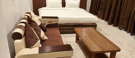 Un dormitorio con una cama, un sofá y una mesa de madera.