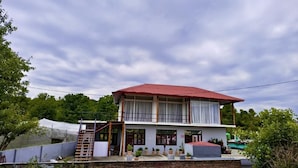 Kaksikerroksinen rakennus, jossa on punainen katto, useita ikkunoita ja parveke.