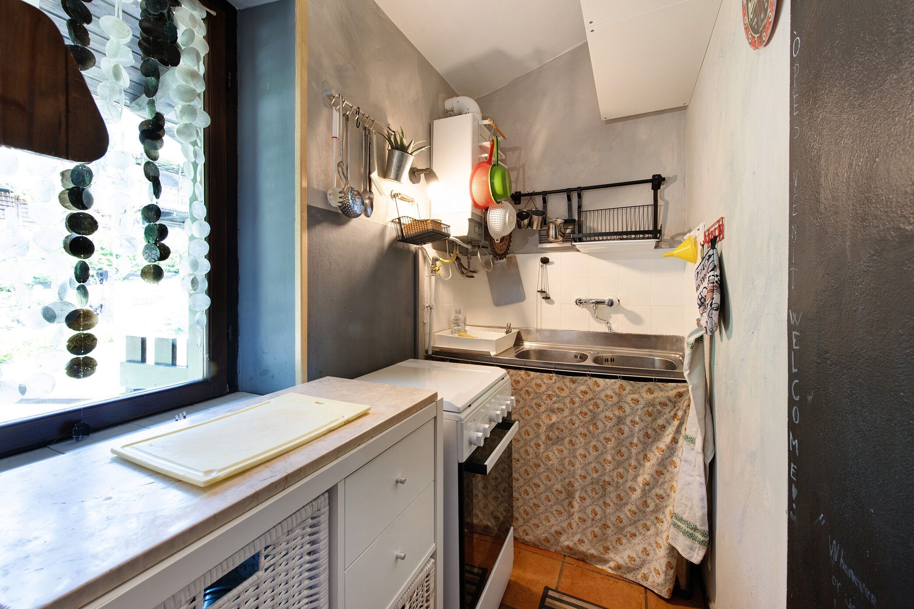 A compact kitchen with a window, a white stove, and a sink.