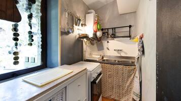 A compact kitchen with a window, a white stove, and a sink.