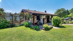 A house with a tiled roof, a garden with various plants, and a wooden fence. - ‘Baita Piero e Afra’ Apartment with Mountain View, Balcony and Wi-Fi (Treviso Bresciano)
