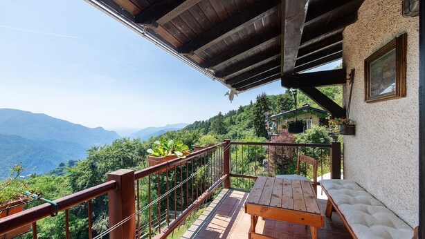 A wooden deck with a table and bench, overlooking a mountainous landscape. - ‘Baita Piero e Afra’ Apartment with Mountain View, Balcony and Wi-Fi (Treviso Bresciano)