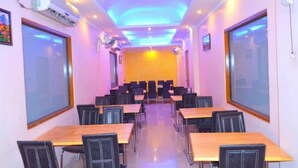 A conference room with tables and chairs, air conditioning units, and ceiling fans.