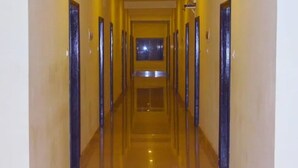 A long, narrow hallway with doors on both sides, leading to a central area with a window.