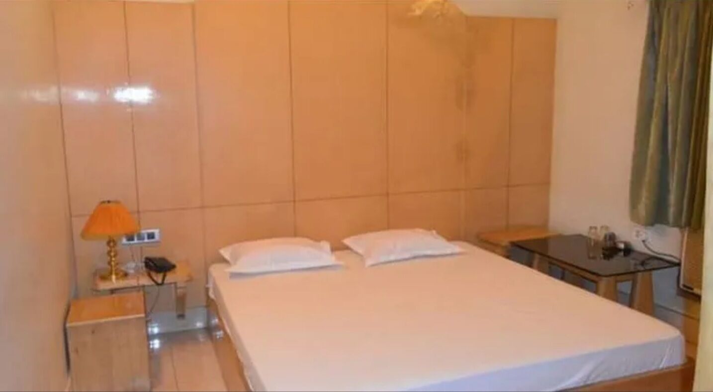 A hotel room with a bed, a nightstand, a lamp, and a small table.