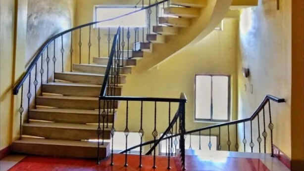 A staircase with a curved design, metal railings, and a red carpeted floor.