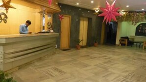 A hotel reception area with a counter, a receptionist, and decorative star-shaped ornaments.