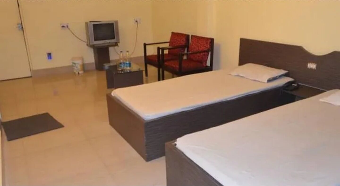 A hotel room with two beds, a television, a chair, and a small table.