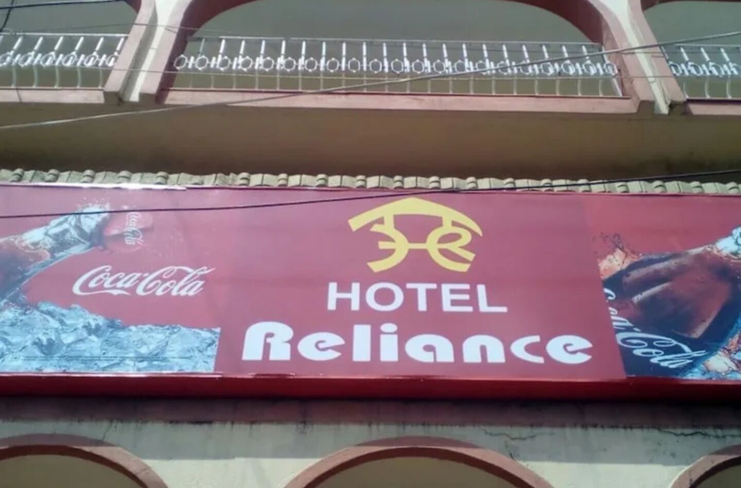 A hotel sign with the name 'HOTEL Reliance' and a Coca-Cola advertisement.