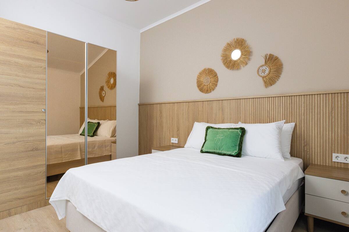 Une chambre à coucher comprenant un lit, une table de chevet, un miroir et des éléments de décoration murale.