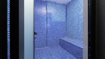Une salle de bain avec des carreaux de mosaïque bleus, une porte et un banc.