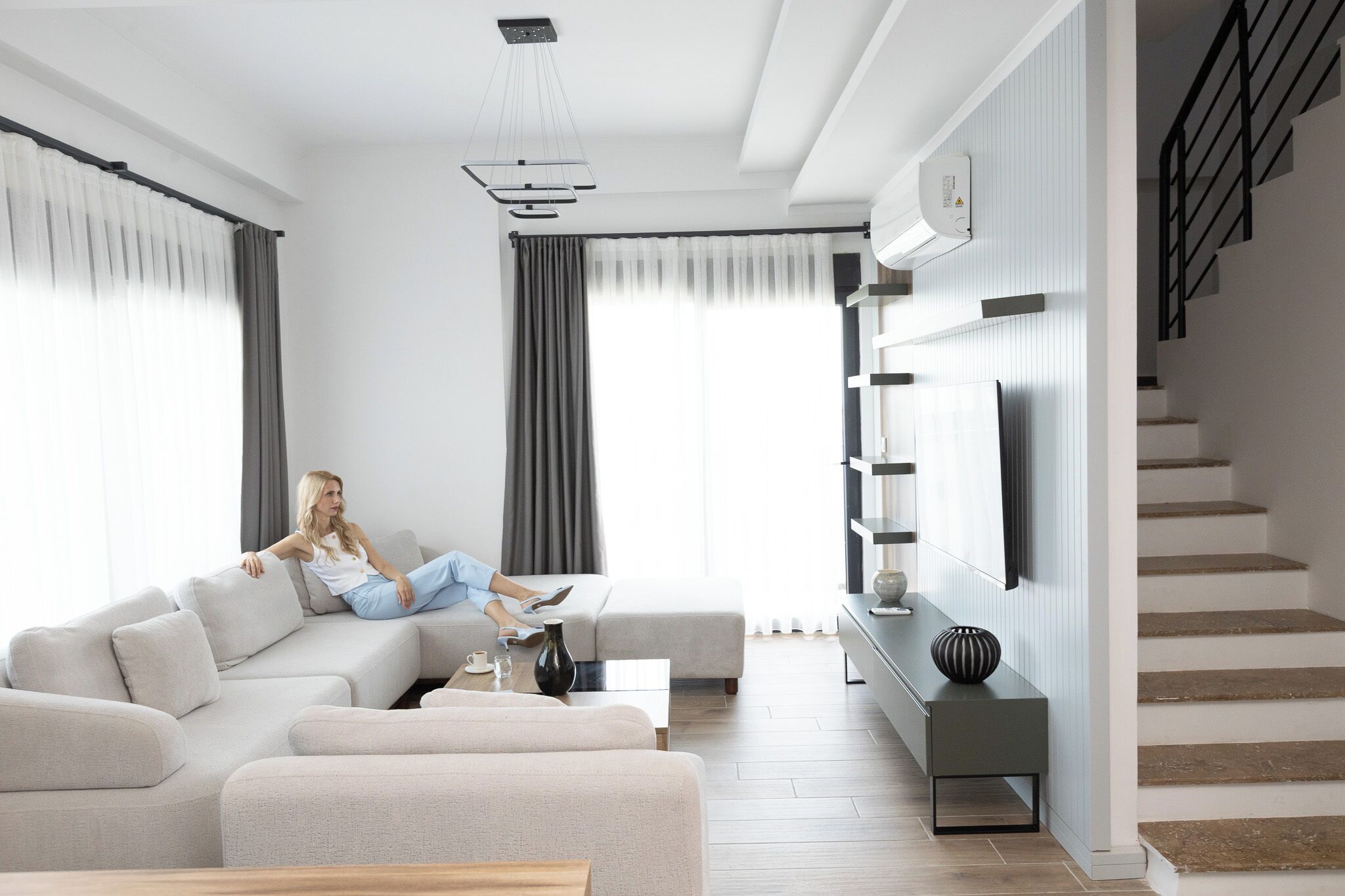 A modern living room with a sofa, coffee table, and a TV mounted on the wall.
