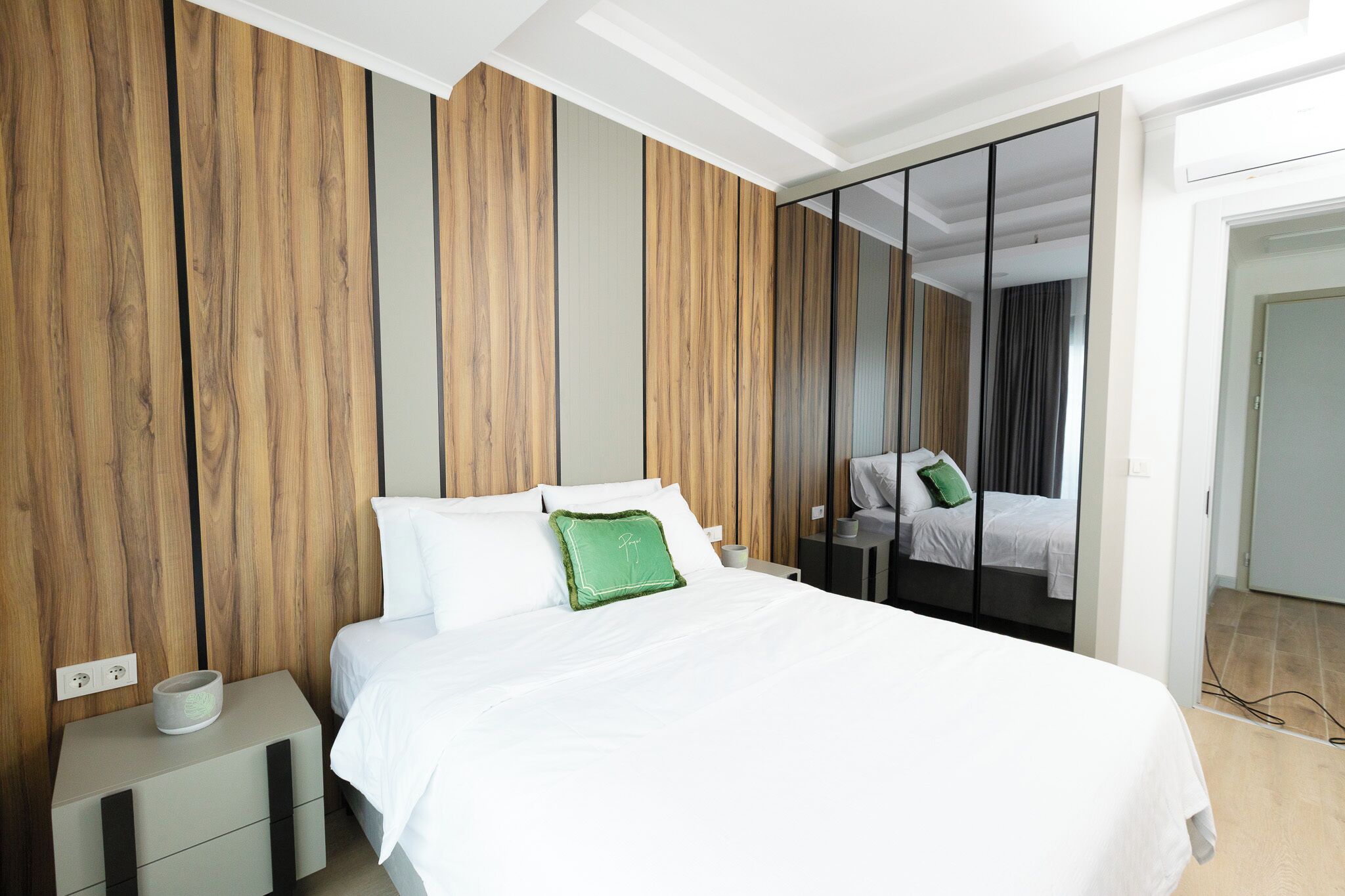 Une chambre à coucher moderne avec un lit, une table de chevet et un meuble-miroir.
