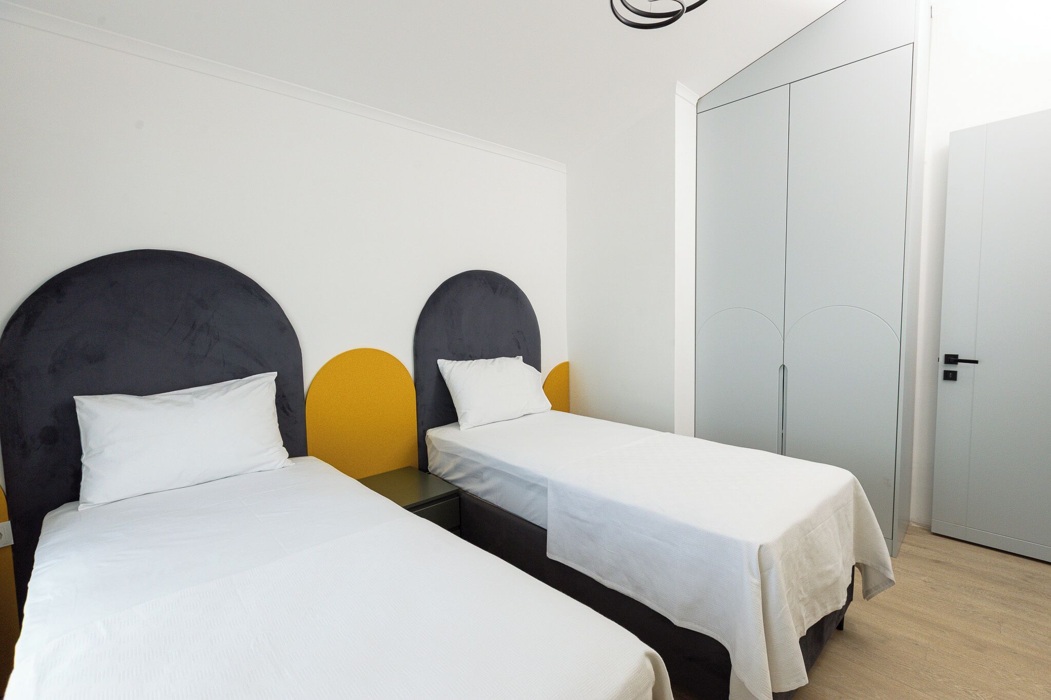 Ein Hotelzimmer mit zwei Einzelbetten, einem Kleiderschrank und einer Tür.