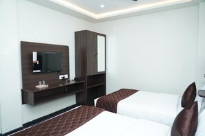 A hotel room with two beds, a TV mounted on the wall, a wardrobe, and a small shelf with a mirror and a phone. - Lakshmi Residency - A Boutique Hotel (Mayiladuthurai)