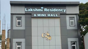 A building with a sign reading 'Lakshmi Residency & Mini Hall' and a logo with 'GS' and a peacock.