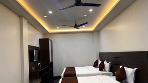 A hotel room with two beds, a ceiling fan, recessed lighting, a TV, and a wardrobe.