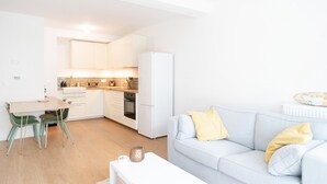 Una cocina moderna con armarios blancos, un refrigerador y un comedor con mesa y sillas.