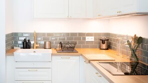 Una cocina moderna con armarios blancos, encimera de madera, un lavamanos y salpicadero.