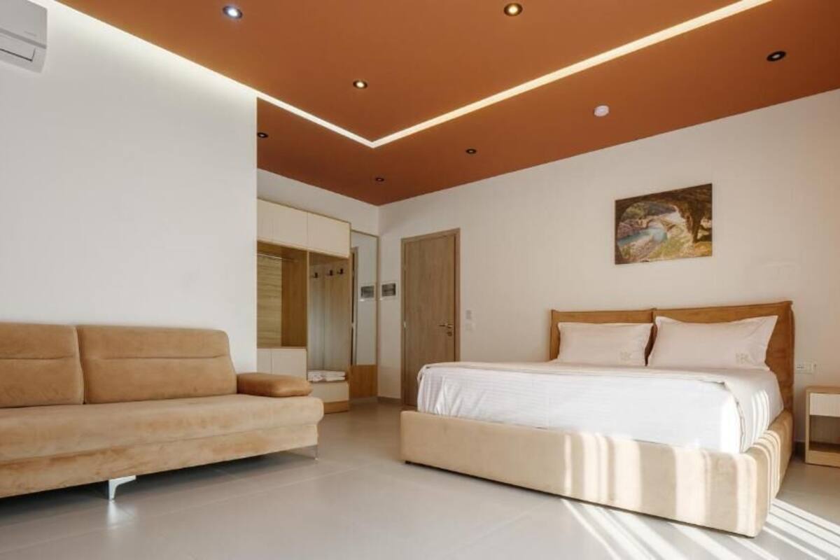 A bedroom with a bed, a sofa, a bedside table, and a painting on the wall.