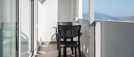 A balcony with a table and chairs, a glass door, and a view of the landscape.