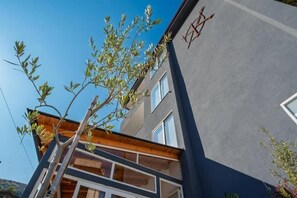 Ein modernes Gebäude mit grauer Fassade, mehreren Fenstern und einem sichtbaren Balkon.