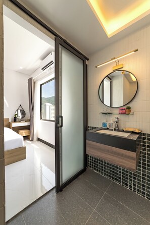 A modern bathroom with a large mirror, a sink, and a shower area. - Minimalist-style private villa with unique arched gatewat design & private pool (Đà Nẵng)