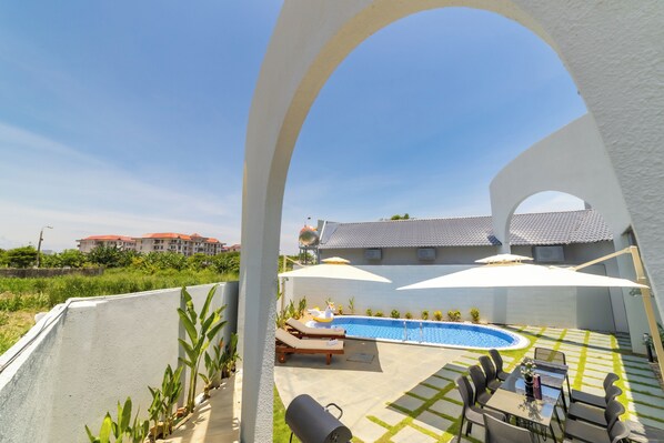 A pool area with lounge chairs, a barbecue grill, and umbrellas.
