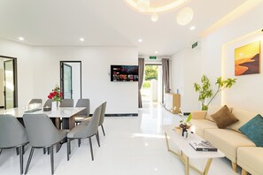 A modern hotel lobby with a dining area, a sofa, and a TV displaying movies.