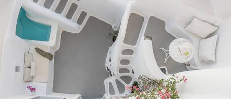 Un interior blanco con una bañera, una mesita con una silla y un ventanal.