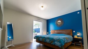 A bedroom with a bed, a nightstand, a wall-mounted mirror, and a ceiling light fixture. - Villa 5 minutes from the beach and Les Sables d'Olonne (Talmont-Saint-Hilaire)