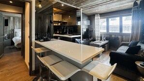 Eine moderne Küche mit einer zentralen Kochinsel, Barhocker und einem Essbereich mit einer Couch und einem Couchtisch.