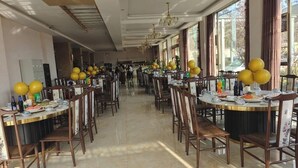 Un grand espace dédié à la salle à manger, avec des tables rondes, des chaises et des ballons jaunes.