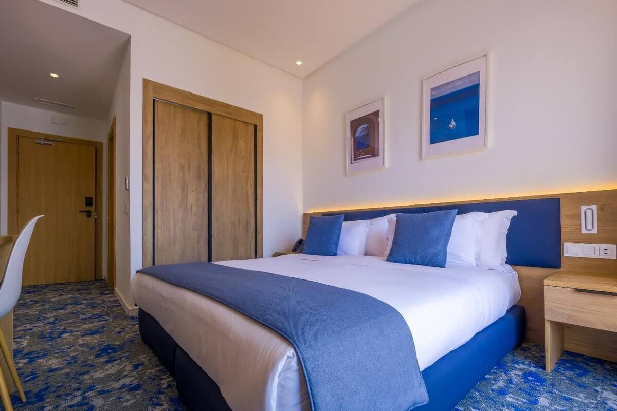 Una habitación de hotel con cama, escritorio, silla y puerta.