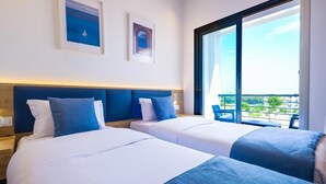 A hotel room with two beds, a large window, and artwork on the wall.