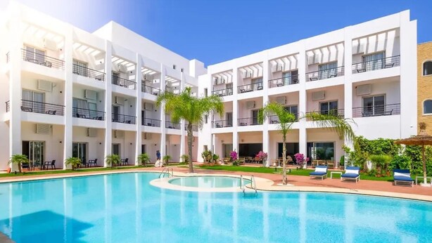 A multi-story hotel with a swimming pool, outdoor seating, and balconies.