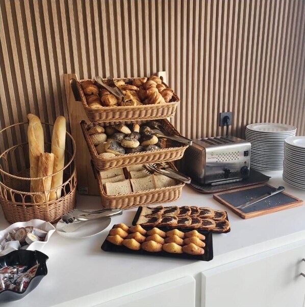 Una mesa de buffet con pan, pastelería y un tostador.