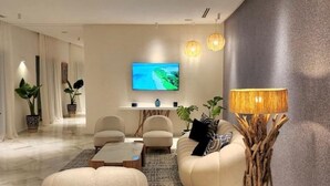 A modern living room with a flat-screen TV, comfortable seating, and a decorative lamp.