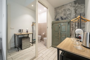 Ein modernes Badezimmer mit Dusche, Toilette und einem Holztisch mit Gläsern und einem Wasserkocher.