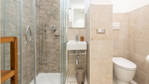 Un baño con cabina de ducha de vidrio, un lavamanos blanco y un inodoro.