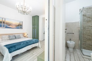 Un dormitorio con cama, mesita de noche, candelabro y un cuadro en la pared.
