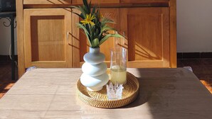 A living room with a flat-screen TV, wooden cabinet, and a table with a vase and glass. - SEASIDE STUDIO (Calcatoggio)