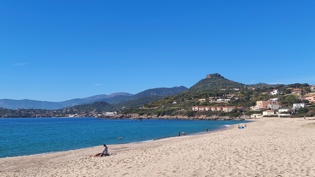 A beach with clear blue water, a sandy shore, and a mountain in the background. - SEASIDE STUDIO (Calcatoggio)