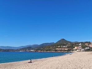 A beach with clear blue water, a sandy shore, and a mountain in the background. - SEASIDE STUDIO (Calcatoggio)