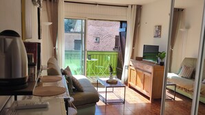 A living room with a sofa, coffee table, TV, and a balcony with a view. - SEASIDE STUDIO (Calcatoggio)