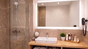 Une salle de bain moderne avec une douche à parois de verre, un lavabo blanc, un miroir et des toilettes.