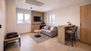 Un espace de vie moderne comprenant un canapé, une table basse, un téléviseur et un petit coin cuisine.
