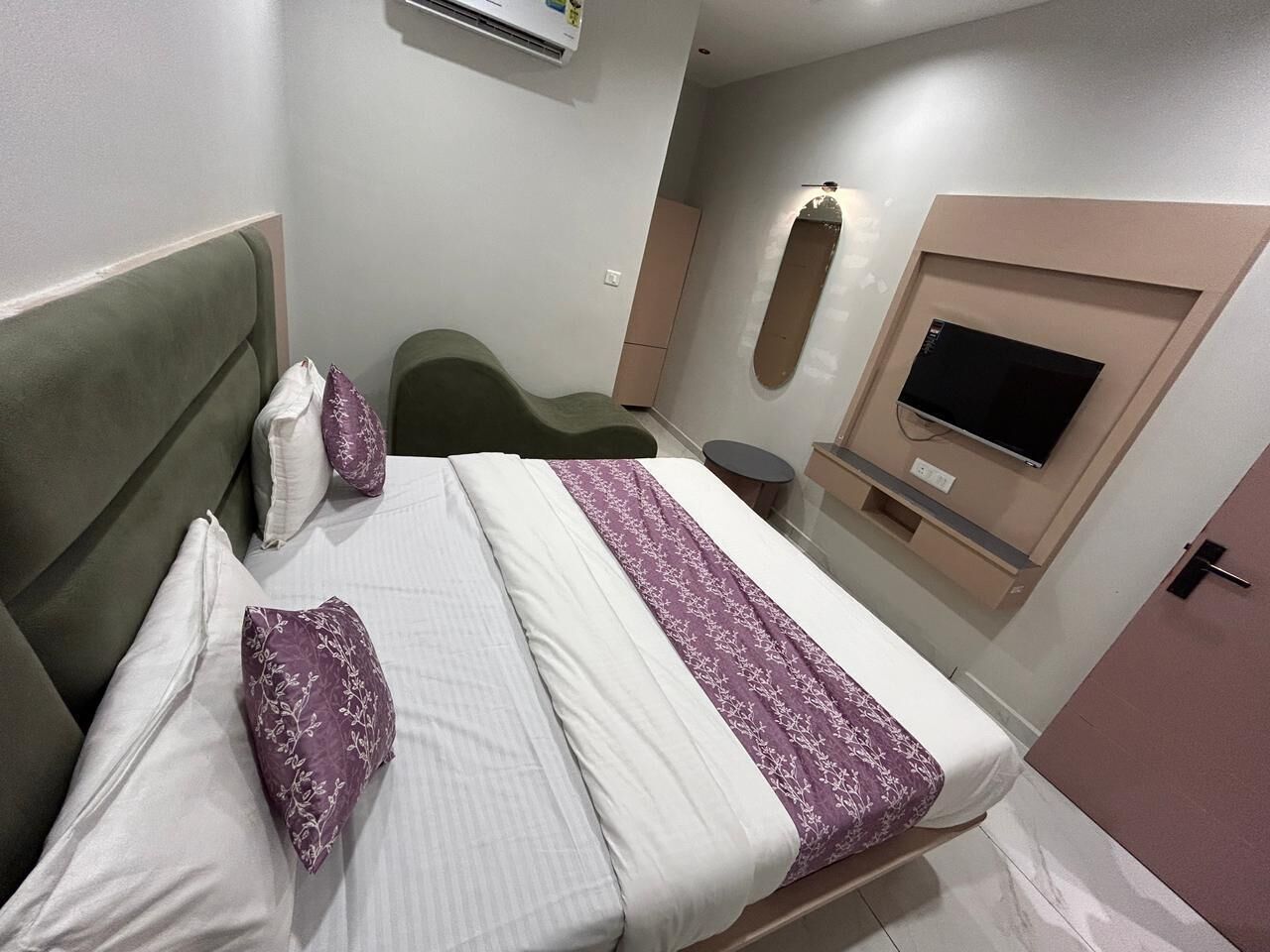Ein Hotelzimmer mit einem Bett, einem Fernseher, einem kleinen Tisch und einem Sessel.