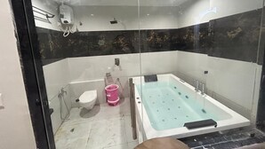 A bathroom with a glass shower enclosure, a bathtub, and a toilet. - Hotel Prime Elite (Ahmedabad)