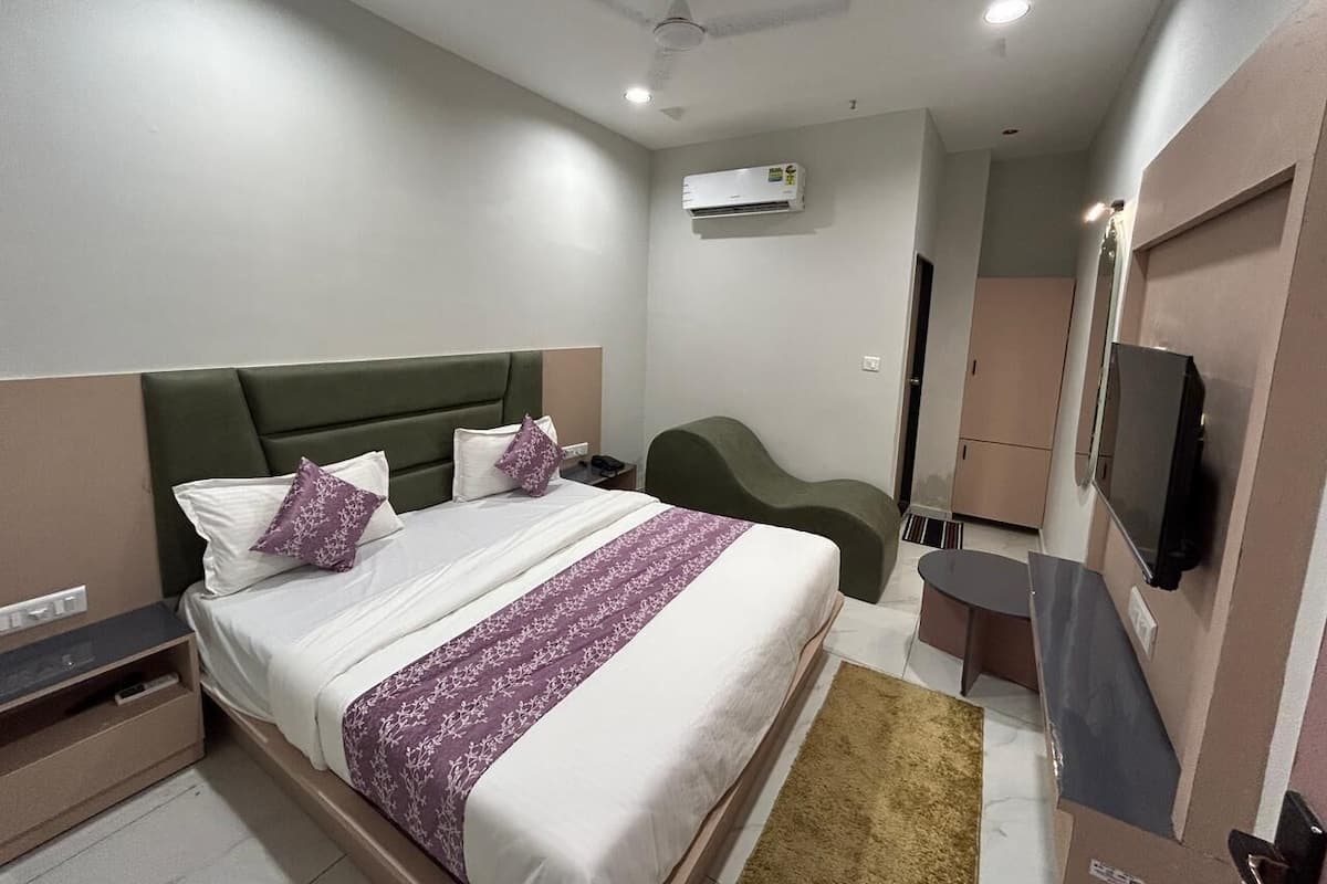 A modern hotel room with a bed, bedside table, TV, and a ceiling fan.